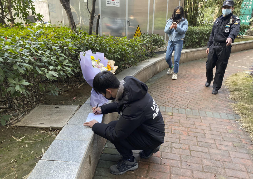 A security guard stands neaby as a man visiting the Wuhan Central Hospital leaves flowers in memory of Li Wenliang, the whistleblower doctor who sounded the alarm and was reprimanded by local police for it in the early days of Wuhan's pandemic, prior to the anniversary of his death, in central China's Hubei province, Saturday, Feb. 6, 2021. Dr. Li Wenliang died in the early hours of Feb. 7 from the virus first detected in this Chinese city. A small stream of people marked the anniversary at the hospital. The 34-year-old became a beloved figure and a potent symbol in China after it was revealed that he was one the whistleblowers who authorities had punished early for “spreading rumors” about a SARS-like virus. (AP Photo/Ng Han Guan)