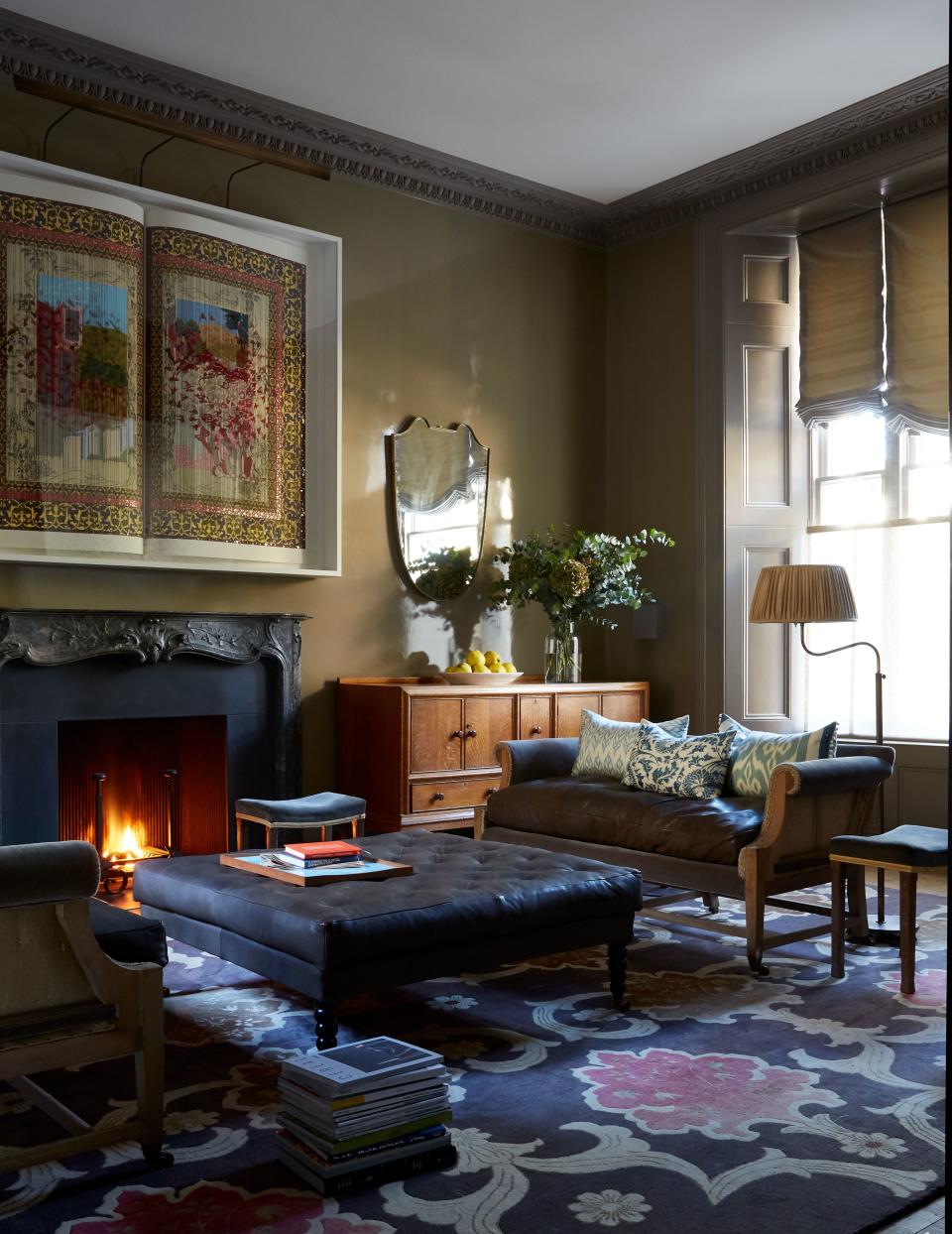 In the reception room, mirrors by Fiona McDonald and a lacquer wall finish by Will Foster Studios add luster to cozy leather sofas by Howe, patterned cushions by Yastik, and vintage sideboards from Miles Griffiths Antiques. An antique table lamp from Howe, two coronation stools in original upholstery, and a Lassco French revival fireplace complete the scene. “It becomes even more beautiful with each viewing,” says the homeowner of the Shahzia Sikander artwork that hangs above the fireplace.