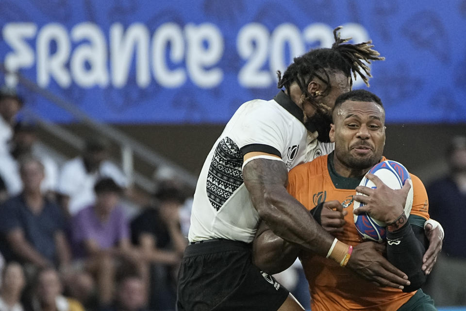 Australia's Samu Kerevi, right, is tackled by Fiji's Waisea Nayacalevu during the Rugby World Cup Pool C match between Australia and Fiji at the Stade Geoffroy Guichard in Saint-Etienne, France, Sunday, Sept. 17, 2023. (AP Photo/Laurent Cipriani)