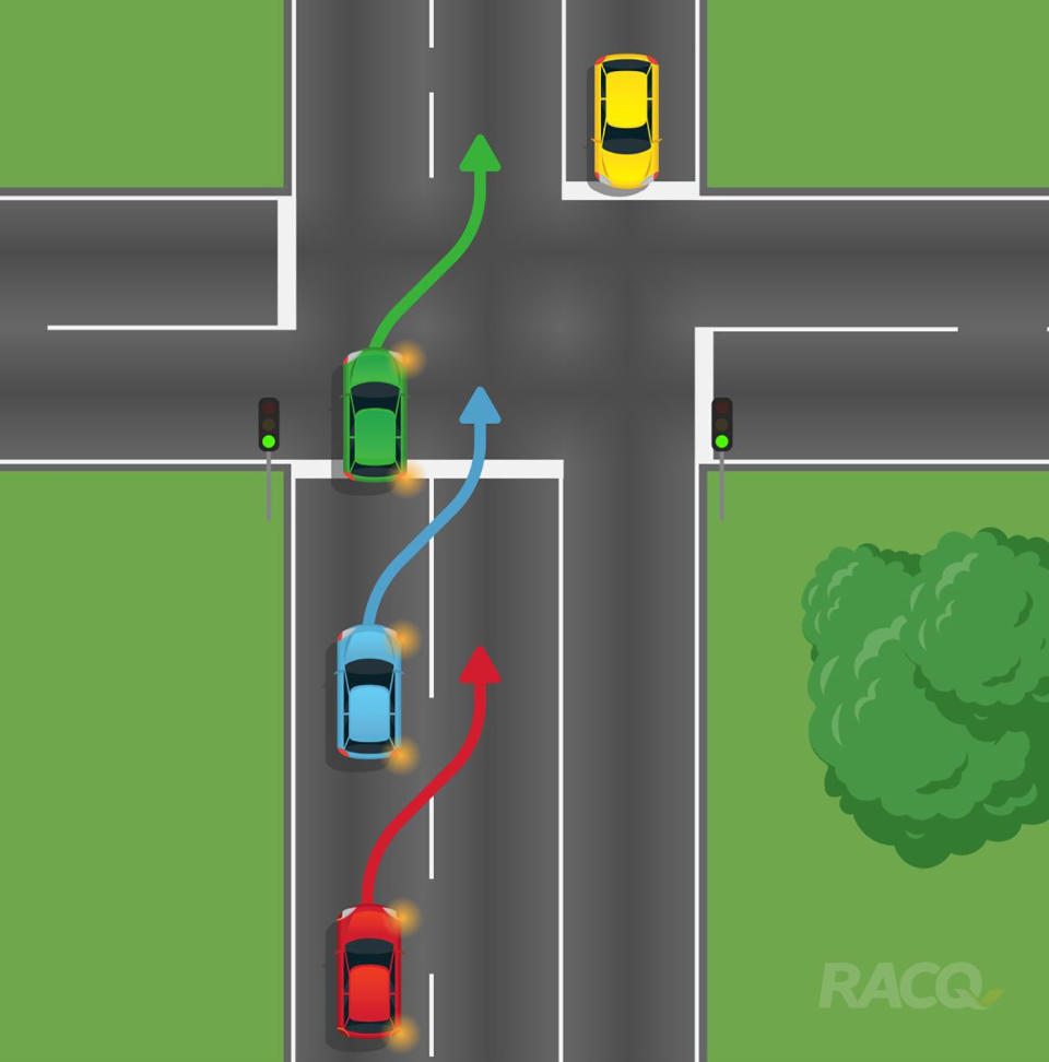 Three cars are pictured preparing to change lanes at an intersection.