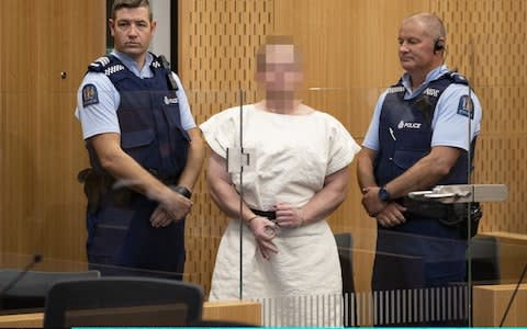 Brenton Tarrant, gestures as he is lead into the dock for his appearance for murder in the Christchurch District Court on March 16, 2019 in Christchurch, New Zealand - Credit: Getty