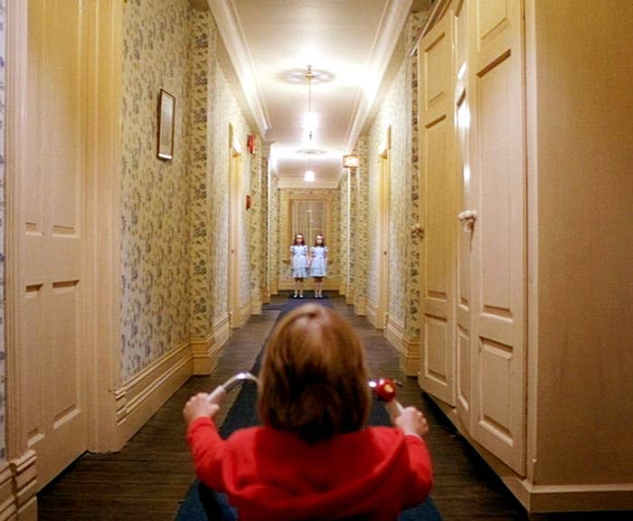A young boy is faced with twins at the end of a hallway
