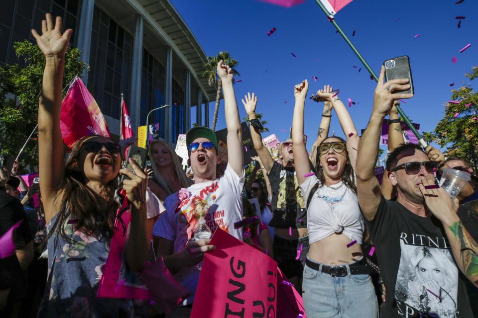 Britney Spears fans cheer and raise their hands with a Los Angeles building in the background