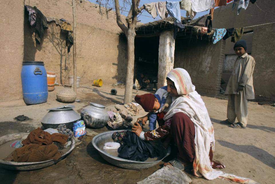 In this Jan. 30, 2014 photo, Pakistani Samia Gul, holds her 11-month-old daughter, Shaista, while doing her laundry at her home in Peshawar, Pakistan. Then the polio virus struck Shaista and she was no longer able to stand, her legs buckling beneath her weight. Her mother cries a lot and wonders what will become of her daughter, already at a disadvantage in Pakistan’s male-dominated society, where a woman’s value is often measured by the quality of her husband. (AP Photo/Mohammad Sajjad)