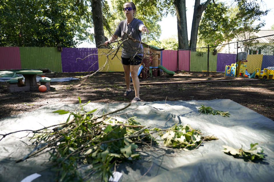 Rachel Grady, lead teacher for Planet Playschool, cleans up branches surrounding her daycare following a storm that hit her town, Tuesday, Aug. 8, 2023, in Mooresville, N.C. (AP Photo/Erik Verduzco)
