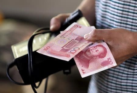 A customer holds a 100 Yuan note at a market in Beijing, August 12, 2015. REUTERS/Jason Lee