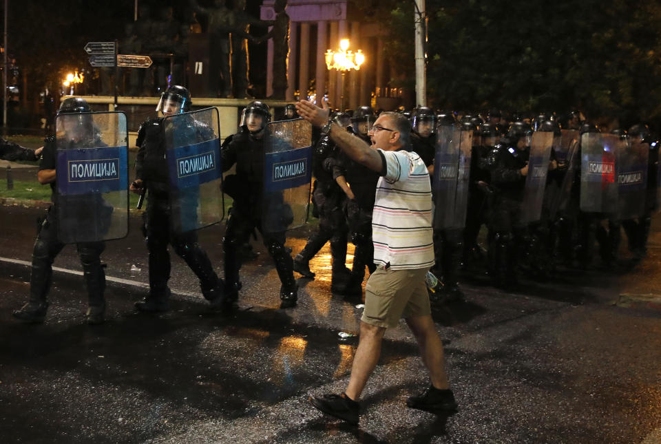 A man reacts as police officers form a cordon during a protest at the parliament building in Skopje, North Macedonia, late Tuesday, July 5, 2022. Violent protests erupted in North Macedonia's capital, Skopje, where demonstrators tried to storm government buildings, after French President Emmanuel Macron last week announced the proposal, which many in the small Balkan country find controversial. (AP Photo/Boris Grdanoski)