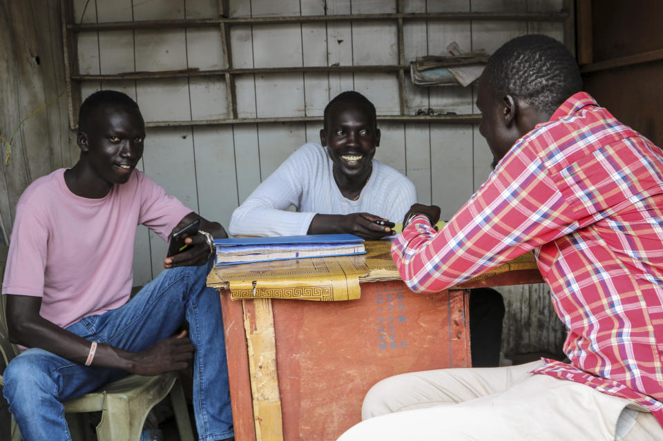 In this photo taken Tuesday, Sept. 10, 2019, Angelo Adud, center, serves customers at his new mobile money kiosk in the capital Juba, South Sudan. South Sudan has launched mobile money, the ability to send and receive funds by phone, in an attempt to boost the economy after a five-year civil war killed almost 400,000 people. (AP Photo/Sam Mednick)