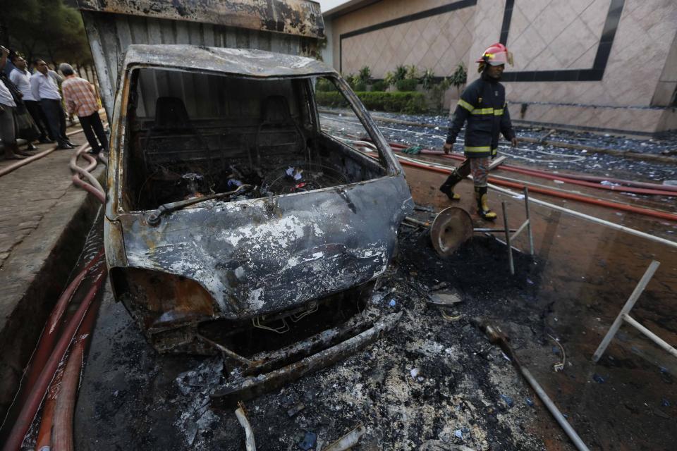 A firefighter walks past a van, which was set on fire by protesting workers, in front of a Standard Group garment factory in Gazipur