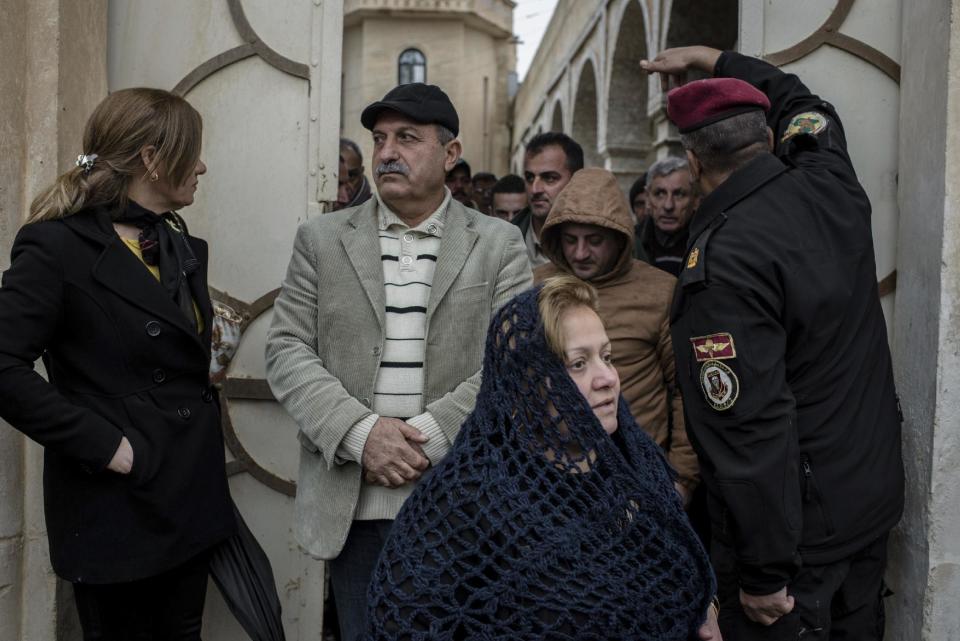 People exit a Christmas Eve's Mass in the Assyrian Orthodox church of Mart Shmoni, in Bartella, Iraq, Saturday, December 24, 2016. For the 300 Christians who braved rain and wind to attend the mass in their hometown, the ceremony provided them with as much holiday cheer as grim reminders of the war still raging on around their northern Iraqi town and the distant prospect of moving back home. Displaced when the Islamic State seized their town in 2014, they were bused into the town from Irbil, capital of the self-ruled Kurdish region, where they have lived for more than two years. (AP Photo/Cengiz Yar)