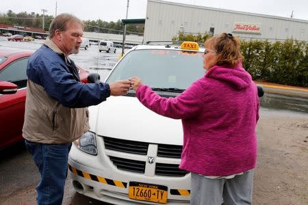 Taxi driver Curtis Seymour hands over his phone headset to his girlfriend as she begins her shift for C&L Taxi in Plattsburgh, New York, U.S., April 26, 2017. REUTERS/Christinne Muschi