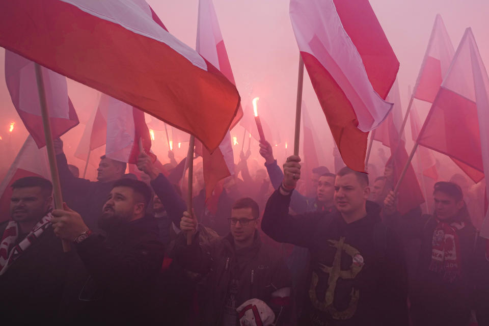 Members of far-right groups light flares as they try to dominate the annual Independence Day march which because of their participation turned violent in recent years, in Warsaw, Poland, on Thursday, November 11, 2021. Warsaw mayor and courts banned this year's event due to its history of violence, but the right-wing ruling authorities defied the ban and gave the march state event status to allow it to go ahead.. (AP Photo/Czarek Sokolowski)