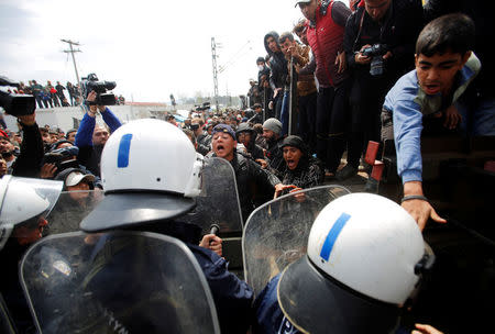 Migrants and refugees scuffle with Greek police after they tried to push a train carriage through a police bus on rail tracks leading to Macedonia at a makeshift camp at the Greek-Macedonian border near the village of Idomeni, Greece, April 11, 2016. REUTERS/Stoyan Nenov
