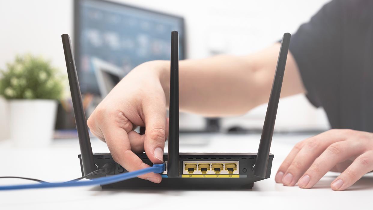  Woman connects an internet cable to the router. 