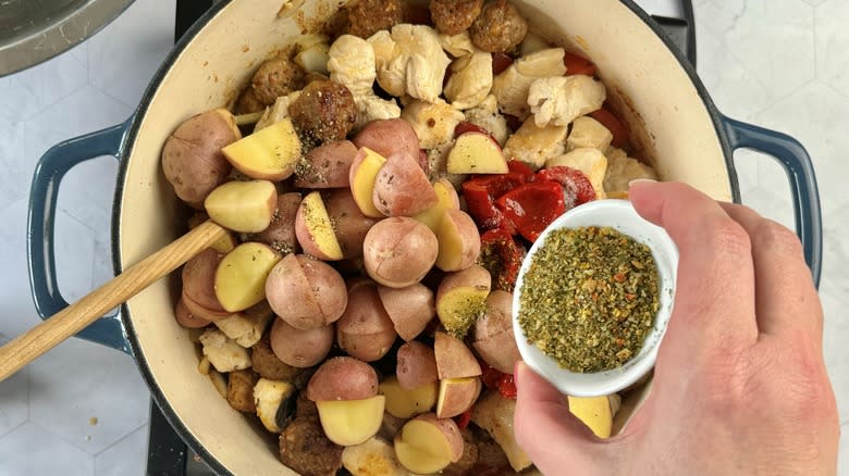 hand adding seasoning to pot