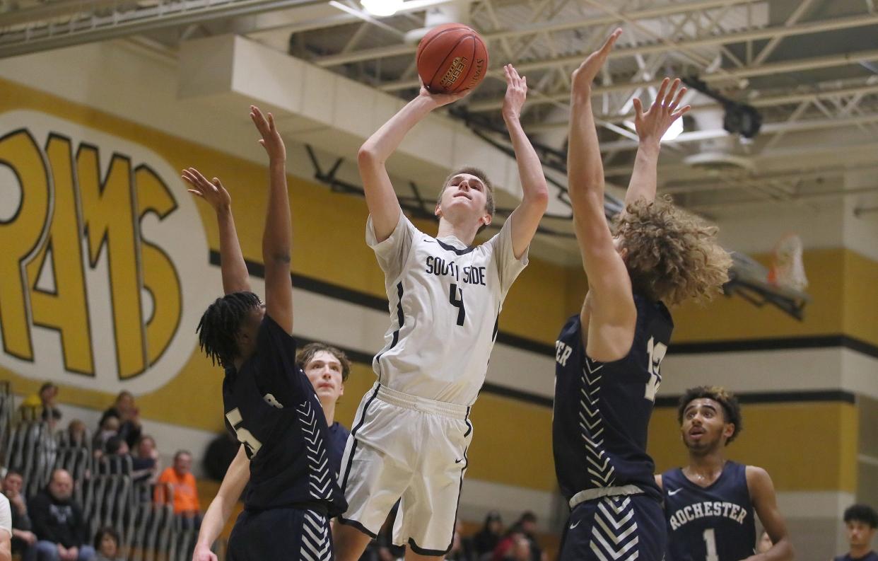 South Side's Jacob Strnisa (4) goes for a two point shot while being guarded by Rochester's Xavier Rigby (5) and Nathan Bills (13) during the second half Friday night at South Side High School.