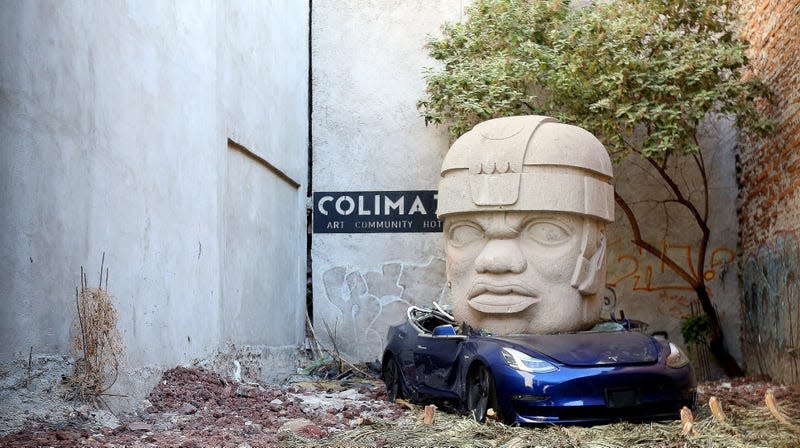 An art installation of Mexican artist Chavis Marmol where a Tesla 3 car is crushed by a nine-ton Olmec-inspired head is pictured at Colima71 Art Community Hotel on March 20, 2024 in Mexico City, Mexico. - Photo: Fernando de Dios (Getty Images)