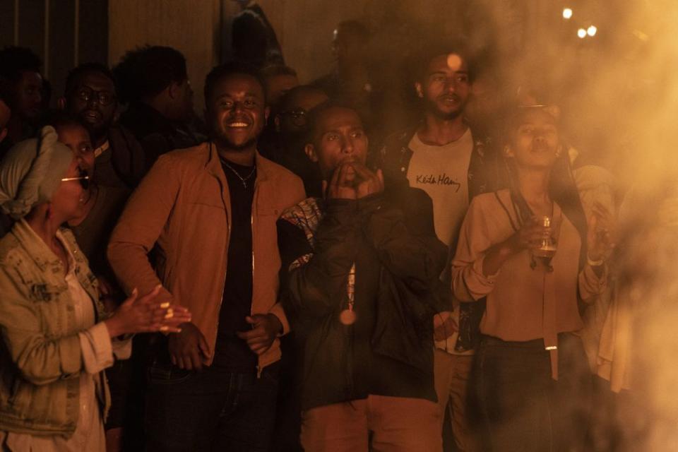 ethiopia new year enkutatash, image of young ethiopian people standing around a bonfire out of frame, smiling and whistling