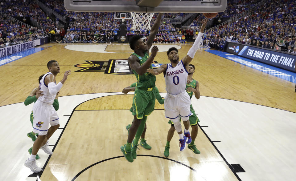 Kansas guard Frank Mason III (0) drives to the basket past Oregon forward Jordan Bell during the first half of a regional final of the NCAA men's college basketball tournament, Saturday, March 25, 2017, in Kansas City, Mo. (AP Photo/Charlie Riedel)