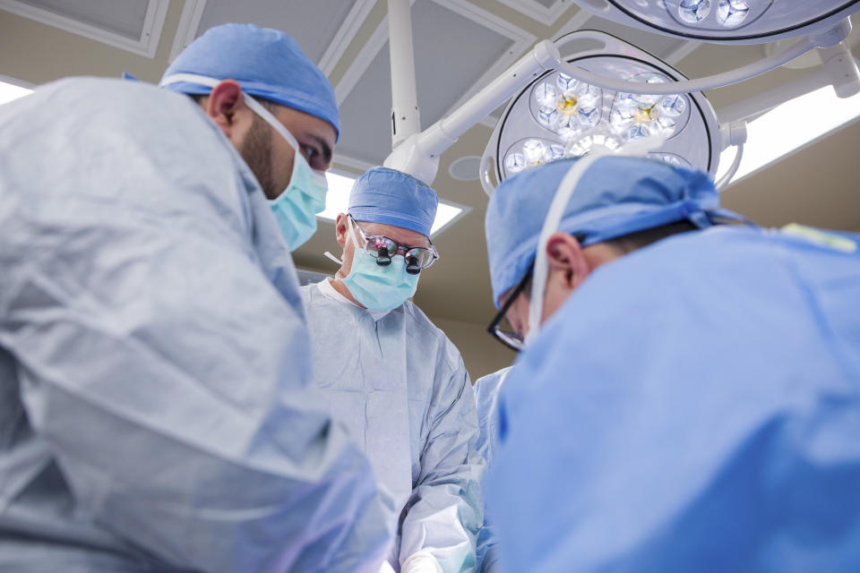 In this photo provided by the Mayo Clinic, Dr. David Lott surrounded by multi-disciplinary team of doctors operate on Marty Kedian at Mayo Clinic Hospital in Phoenix, on Feb. 29, 2024. Kedian regained his voice after surgeons removed his cancerous larynx and, in a pioneering move, immediately replaced it with a donated one. (Mayo Clinic via AP)