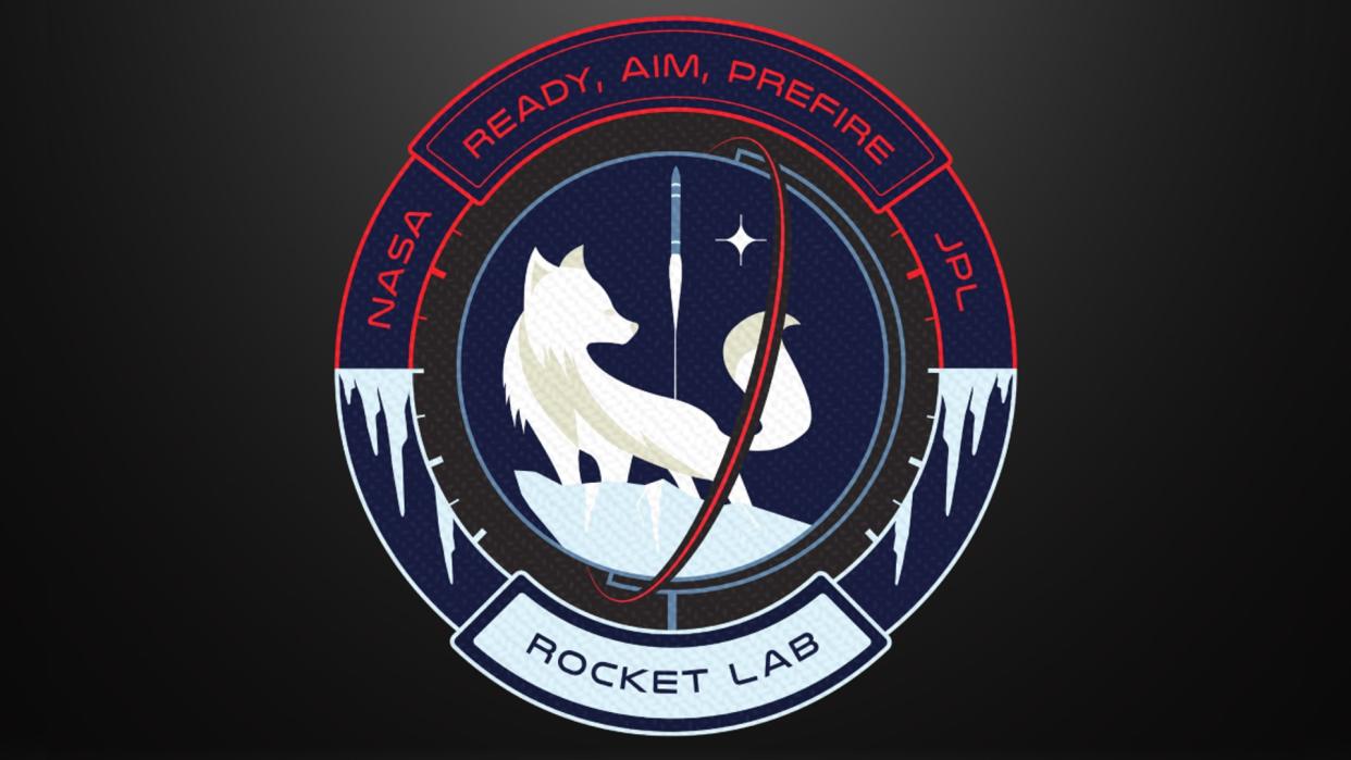  A mission badge showing the white silhouette of an arctic fox against a dark blue background. a white silhouette of a rocket lifts off in the background. 