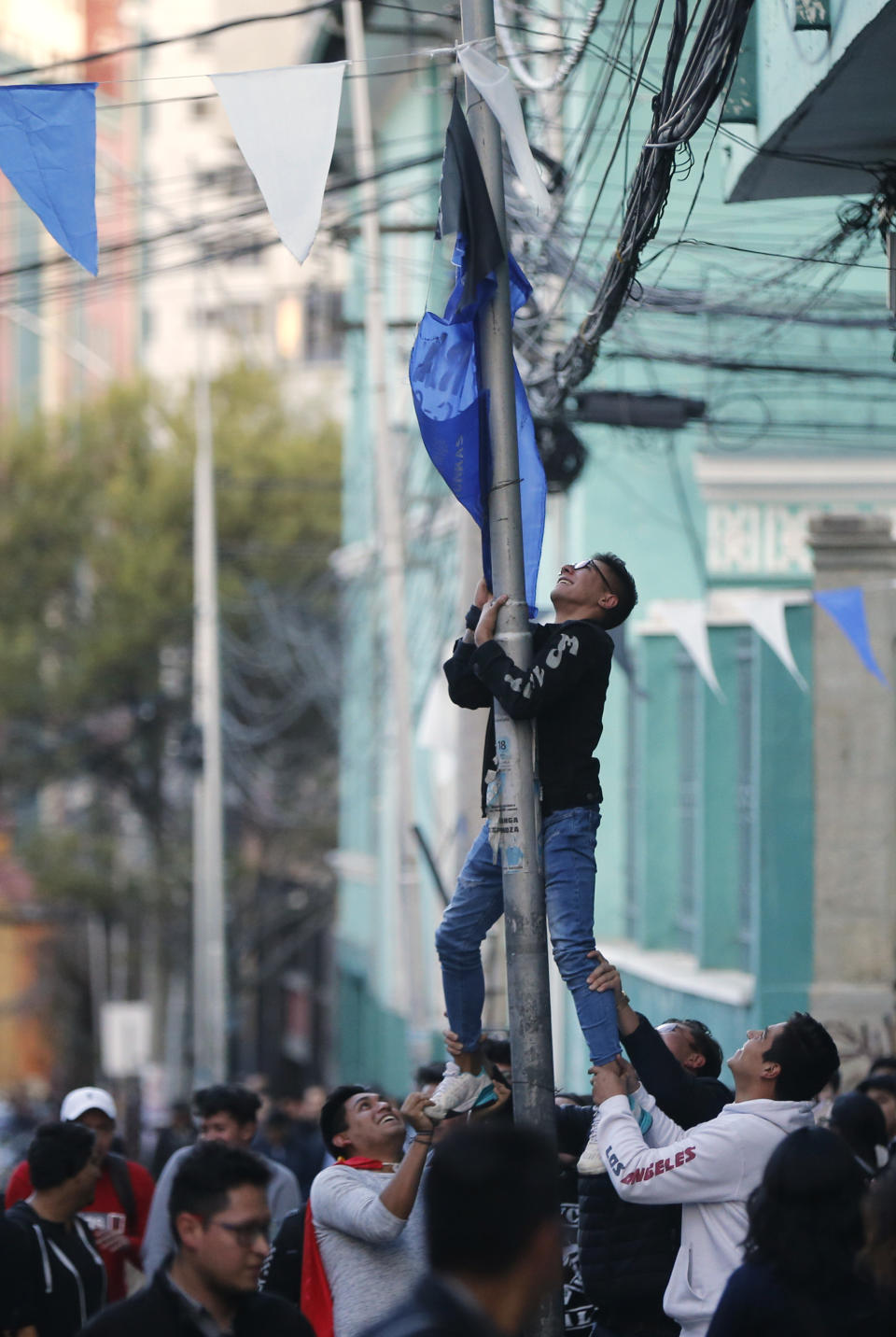 Students work to bring down a banner of the ruling party "Moviemiento al Socialismo" during an anti-government march in La Paz, Bolivia, Tuesday, Oct. 22, 2019. International election monitors expressed concern over Bolivia's presidential election process Tuesday after an oddly delayed official quick count showed President Evo Morales near an outright first-round victory — even as a more formal tally tended to show him heading for a risky runoff. (AP Photo/Jorge Saenz)