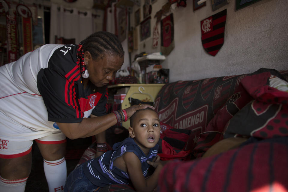 In this May 4, 2014 photo, Maria Boreth de Souza, alias Zica, caresses her five-year-old grandson Hugo before she leaves for Maracana stadium from her home in the Olaria neighborhood of Rio de Janeiro, Brazil. Souza said that at age seven she fled her home because her parents mistreated here. Ten years later, the mother of Brazil's rising star Zico persuaded her to leave the streets. When she was 29, Zico's parents persuaded Souza to return to her home to care for her sick parents who did shortly after she returned. (AP Photo/Leo Correa)