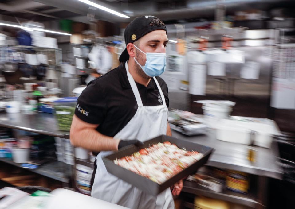 Koby Wexler, the originator of Death by Pizza in Delray Beach, dashes toward an oven with one of his Detroit-style pizzas.