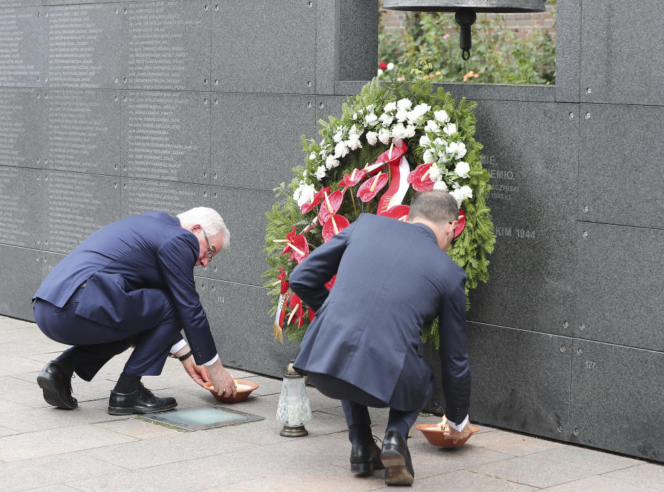 Polish Foreign Minister Jacek Czaputowicz, left, and his German counterpart Heiko Maas, right, pay homage to the victims of the Warsaw Uprising, a failed revolt by Poles against the occupying Nazi German forces, in Warsaw, Poland, Thursday, Aug. 1, 2019 on the 75th anniversary of the start of the two-month battle. (AP Photo/Czarek Sokolowski)