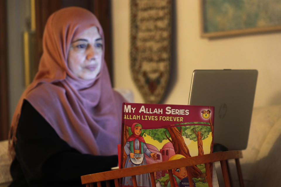 In this Tuesday, April 28, 2020, photo, Shaheen Khan works on her laptop at her Wheeling,Ill., home. During the COVID-19 crisis, Khan now teaches virtually to her students at the Hadi School, a Montessori Islamic school in Schaumburg, Illinois, realizing the increased time at home could be used as an opportunity for reflection "to come back to our roots", and used the Prophet Mohammad traveling to a cave to meditate as an example. AP Photo/Charles Rex Arbogast)