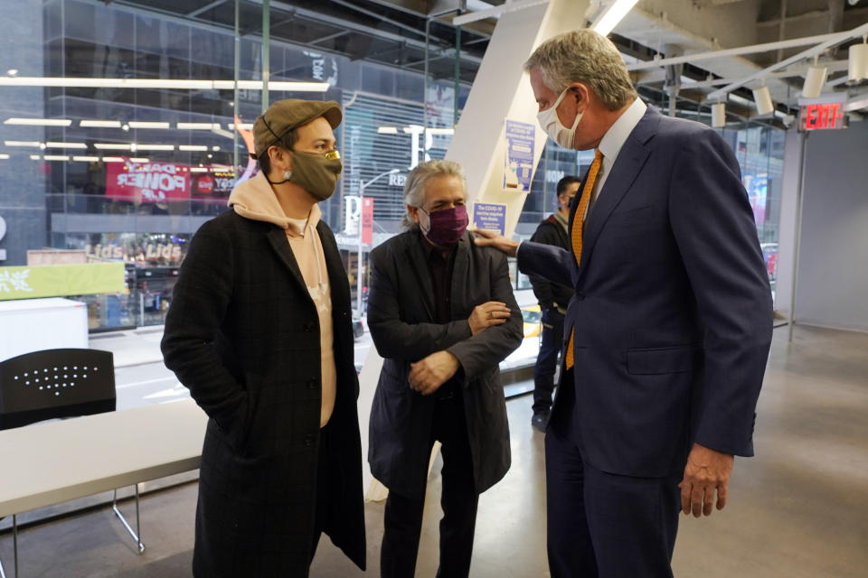 Actor Lin-Manuel Miranda, left, and his father, Luis A. Miranda, Jr., center, talk with New York Mayor Bill de Blasio, before they tour the grand opening of a Broadway COVID-19 vaccination site intended to jump-start the city's entertainment industry, in New York, Monday, April 12, 2021. (AP Photo/Richard Drew, Pool)