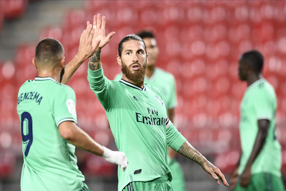 El capitán del Real Madrid Sergio Ramos saluda a Karim Benzema durante el partido contra Granada por la Liga de España en Granada, el lunes 13 de julio de 2020. (AP Foto/José Bretón)