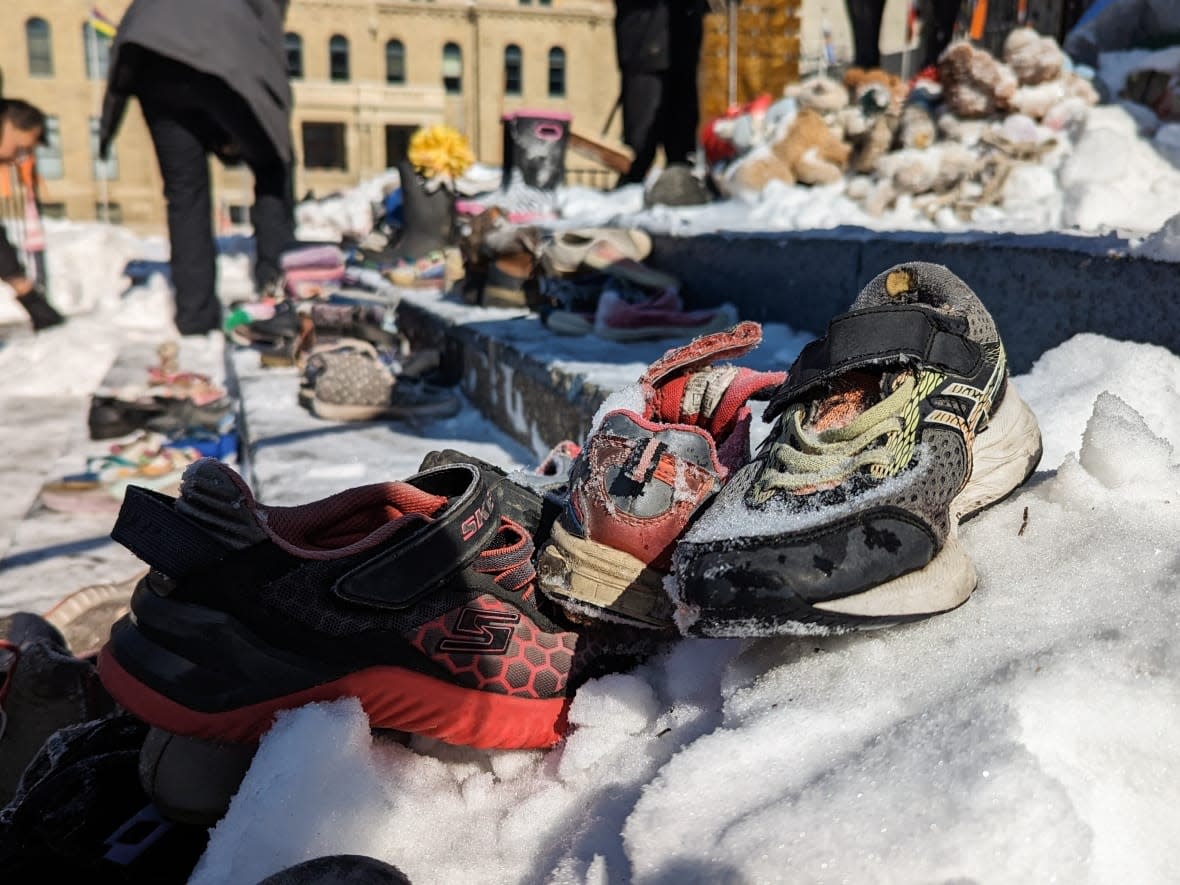 Children's shoes sit on snowy steps at Calgary's City Hall. Volunteers cleaned up the memorial to residential school victims on March 12, 2023. (Tom Ross/CBC - image credit)