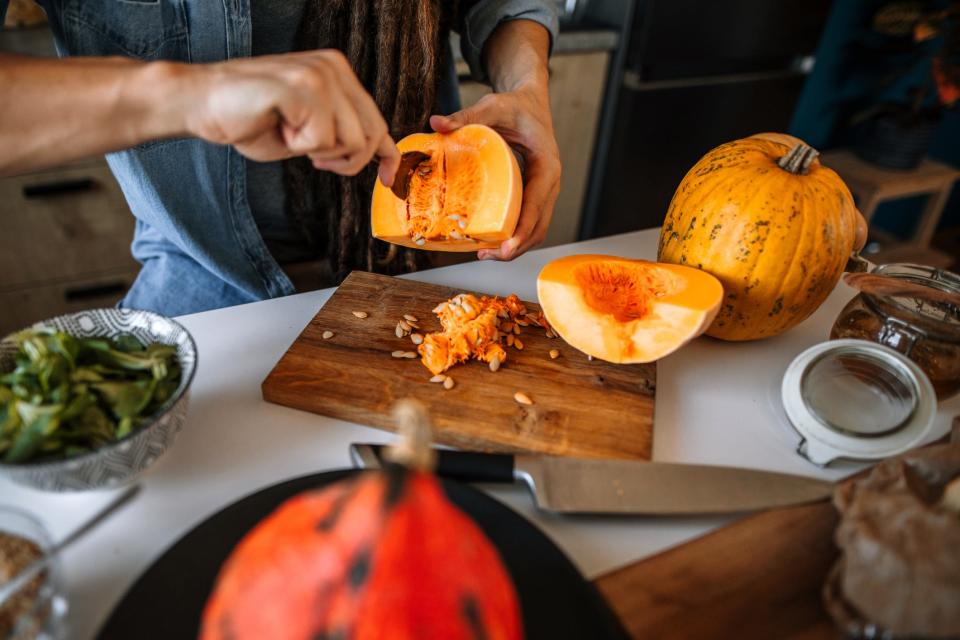 a close up of a person cutting up squash to prepare a meal