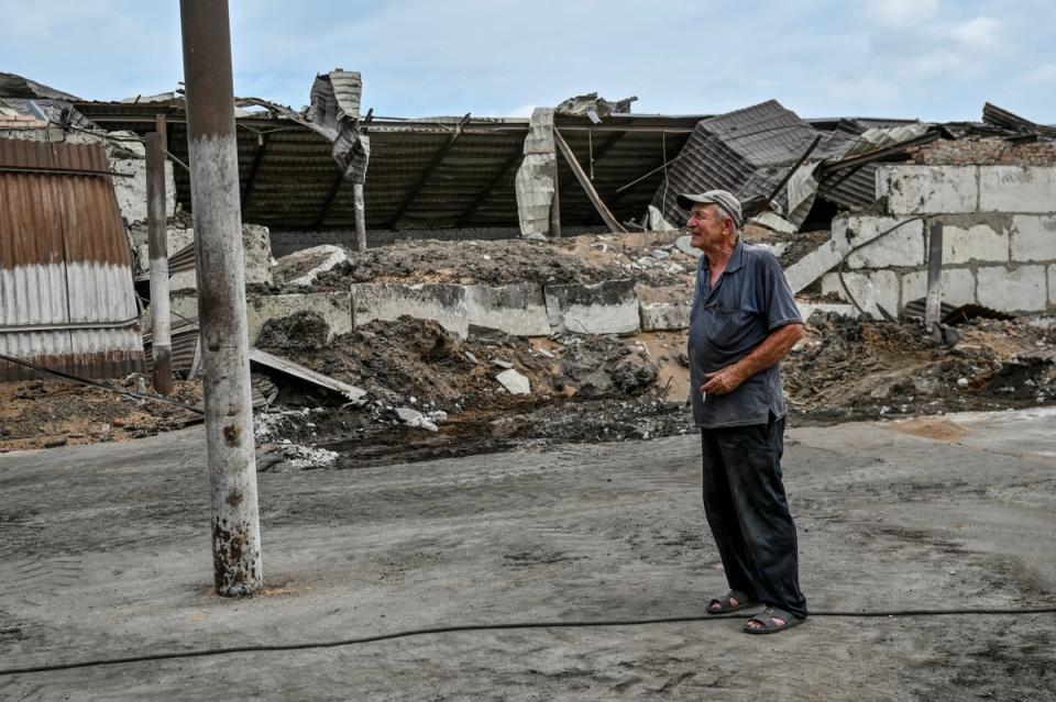 An employee smokes next to a wheat store damaged by a Russian missile strike in the Zaporizhzhia region (Reuters)