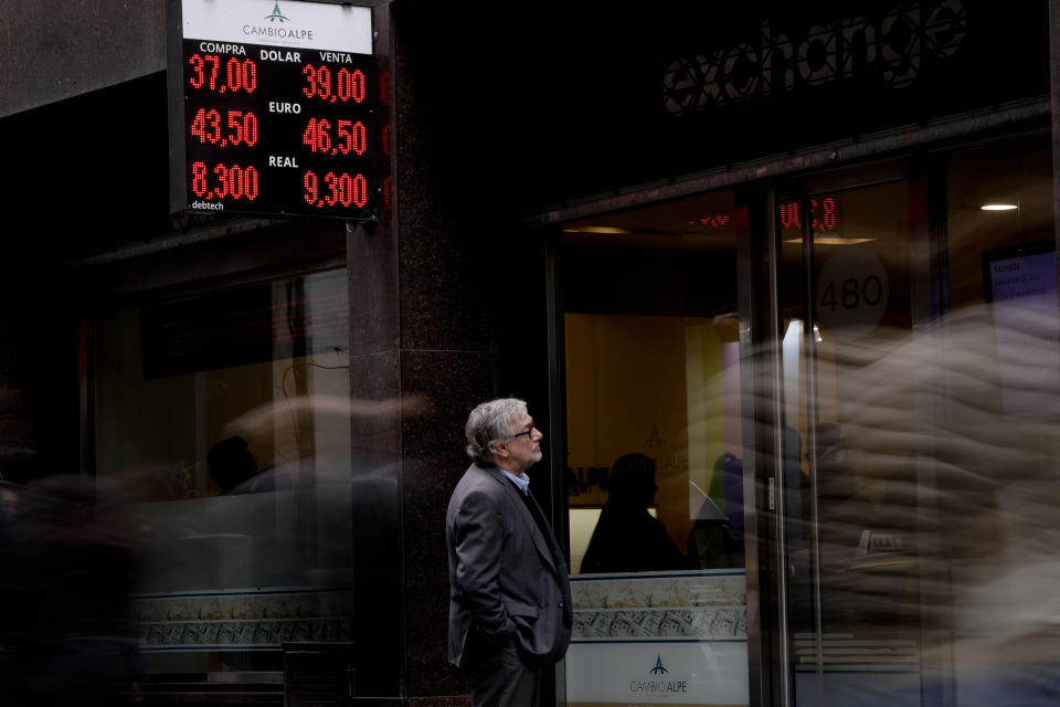 In this Sept. 3, 2018 photo, a man looks at the price of the U.S. dollar and Brazilian real at a money exchange house in Buenos Aires, Argentina. Argentina's President Mauricio Macri has announced new taxes on exports and the elimination of several ministries in a bid to halt economic turmoil that has sent the peso to record lows. (AP Photo/Natacha Pisarenko)