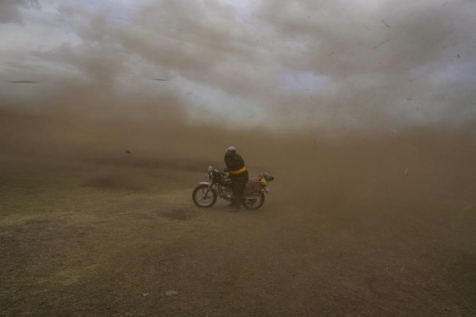 Lkhaebum holds his cap as a sudden dust storm swirls outside his ger in the Munkh-Khaan region of the Sukhbaatar district, in southeast Mongolia, Saturday, May 13, 2023. (AP Photo/Manish Swarup)