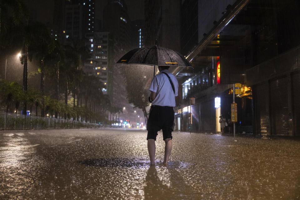 A pedestrian waits for a bus on a flooded street following heavy rainstorms in Hong Kong, Friday, Sept. 8, 2023. (AP Photo/Louise Delmotte)