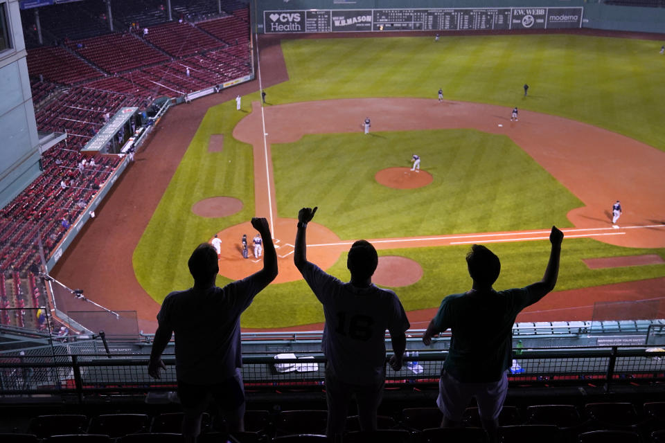 From nearly empty stands, three fans sing "Sweet Caroline," a tradition in the bottom of the eighth inning at Fenway Park, after a rain delay in the May 26 baseball game between the Boston Red Sox and the Atlanta Braves caused the game to be restarted early Thursday, May 27, 2021, in Boston. (AP Photo/Charles Krupa)