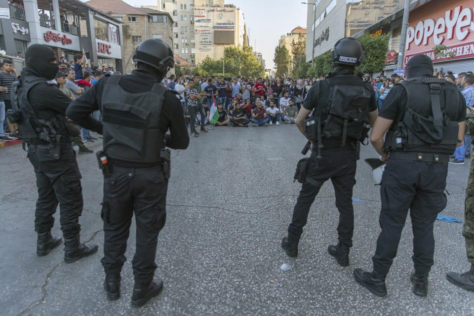 Demonstrators close the road in front of riot police during a rally protesting the death of Palestinian Authority outspoken critic Nizar Banat, in the West Bank city of Ramallah, Saturday, July 3, 2021. Hundreds of Palestinians gathered to demonstrate against President Mahmoud Abbas, hoping to inject new momentum into a protest movement sparked by the death of an outspoken critic in the custody of security forces. (AP Photo/Nasser Nasser)