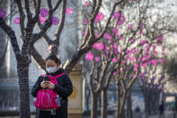 A woman wears a face mask as she walks along a street in Beijing, Wednesday, Jan. 29, 2020. China as of Wednesday has more infections of a new virus than it did in with SARS, though the death toll is still lower. (AP Photo/Mark Schiefelbein)