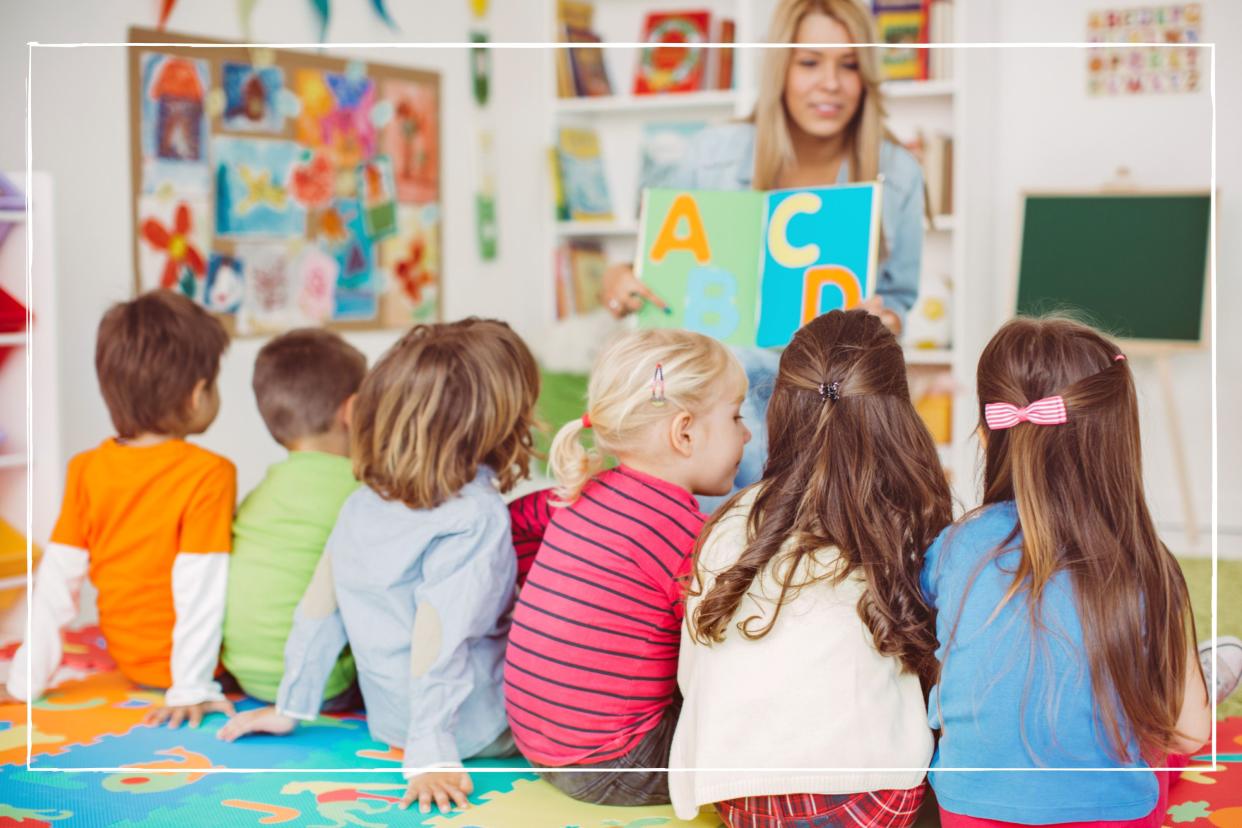  Children sitting on the floor in front of caregiver at nursery. 