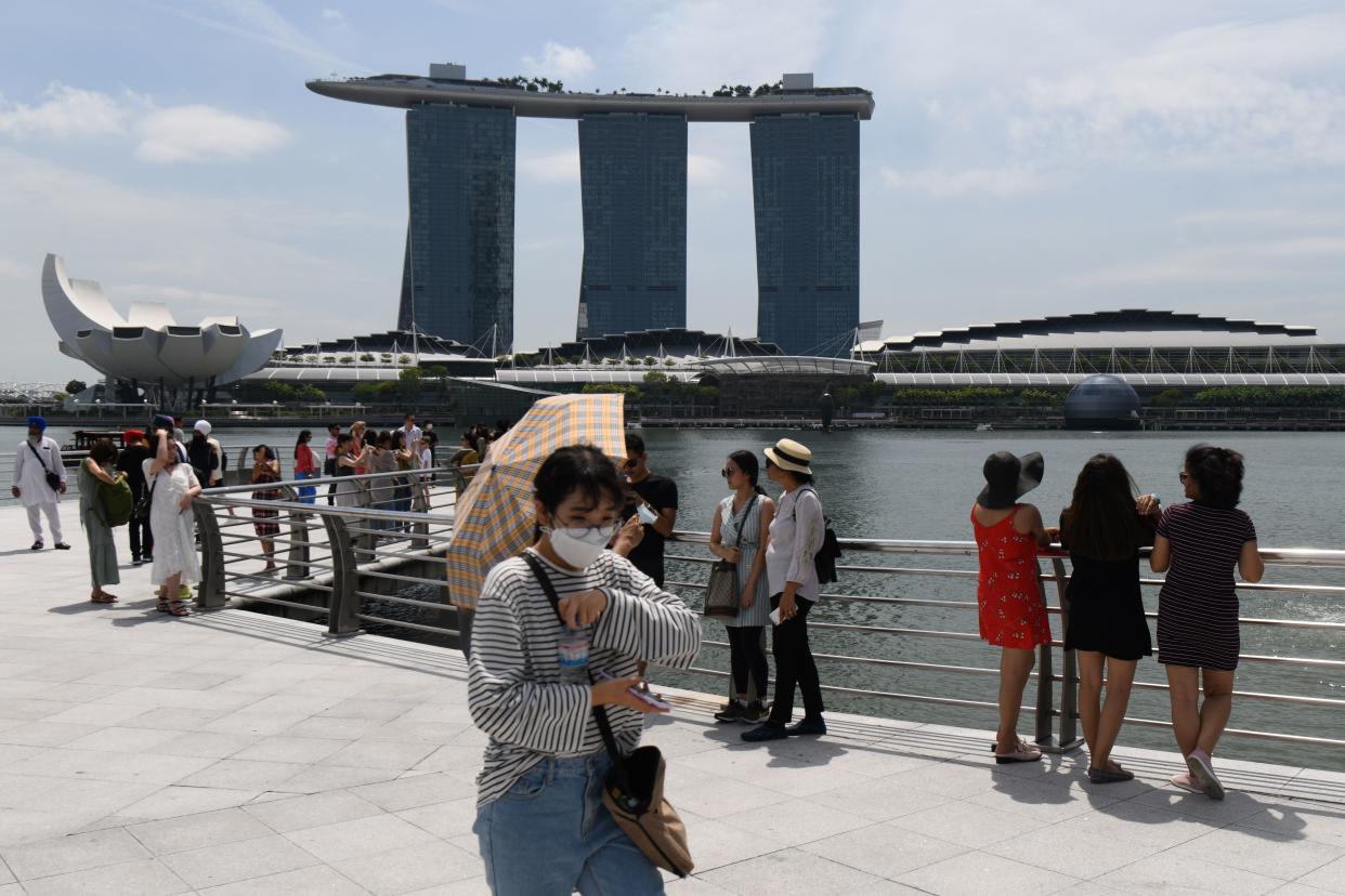 A visitor, wearing a protective facemask amid fears about the spread of the COVID-19 novel coronavirus, walks along Merlion Park. (PHOTO: AFP via Getty Images)