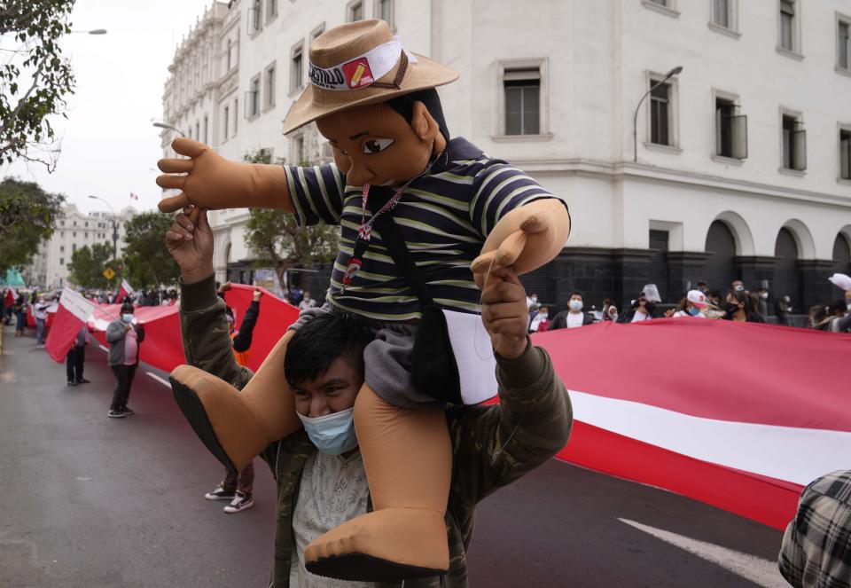 A supporter of presidential candidate Pedro Castillo carries a puppet in Castillo's likeness during a march in Lima, Peru, Wednesday, June 9, 2021. Peruvians are still waiting to learn who will become their president next month as votes from Sunday's runoff election continued to be counted and the tiny difference between the two polarizing populist candidates narrowed. (AP Photo/Martin Mejia)