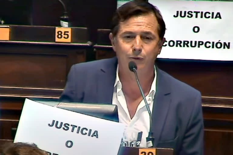 Daniel Lipovetzky, al hablar en el recinto, con los afiches opositores de "Justicia o corrupción"