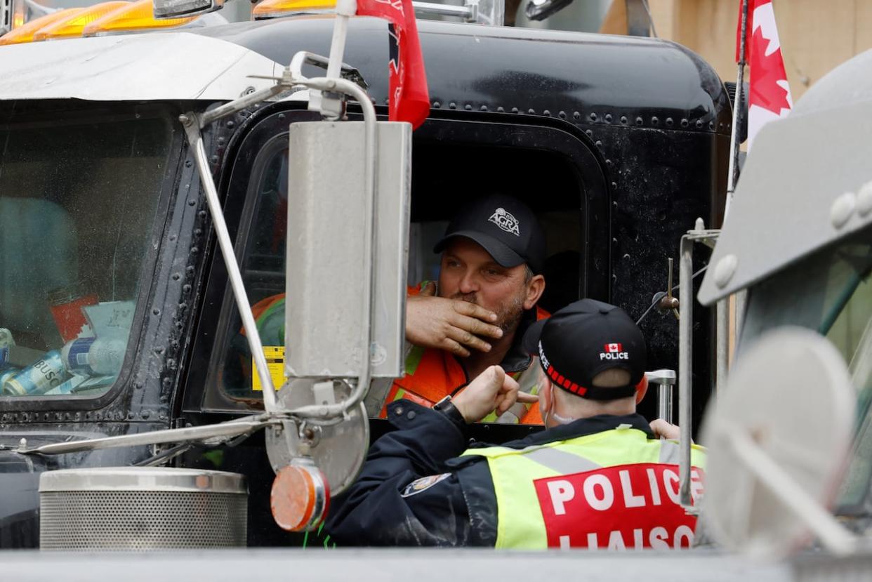 A trucker speaks with a police officer as the truck convoy protest continued in Ottawa Feb. 2, 2022. The defence team for two protest organizers wants more information from police than first shared. (Blair Gable/Reuters - image credit)