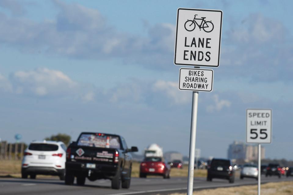 Eastbound motorists on U.S. Highway 98 on Okaloosa Island pass signs that say share the road with bicyclists. Gov. Ron DeSantis signed legislation last year that states no-passing zones do not apply to drivers who safely and briefly drive to the left of center of the road to pass a bicycle or pedestrian.