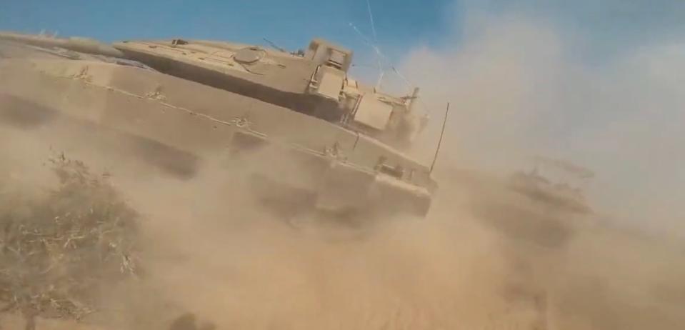 As the Hamas fighter runs toward an Israeli Merkava tank, the barrel of another one is pointing in his direction. (Hamas screencap)