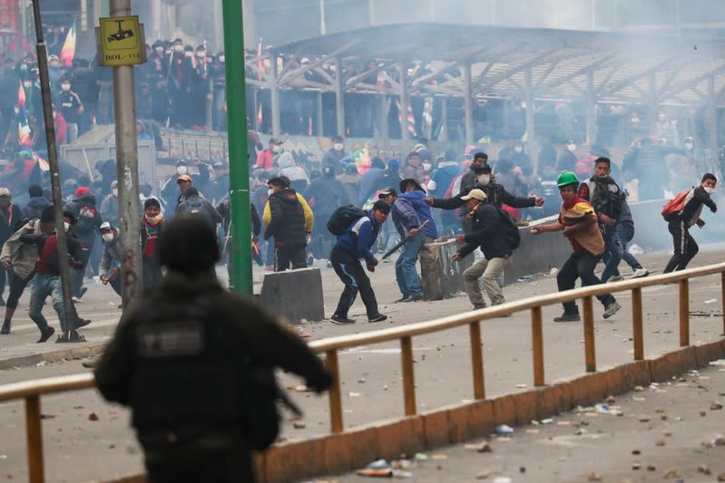 A member of the security forces and supporters of former Bolivian President Evo Morales react during clashes in La Paz