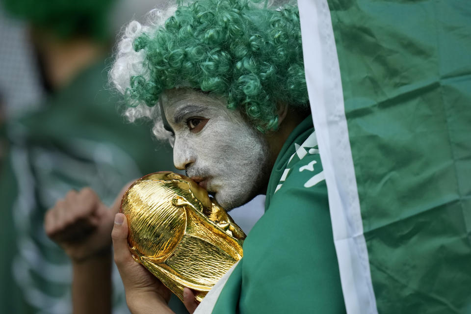 A Saudi Arabia fan kisses a copy of the World Cup trophy prior of the World Cup group C soccer match between Poland and Saudi Arabia, at the Education City Stadium in Al Rayyan , Qatar, Saturday, Nov. 26, 2022. (AP Photo/Francisco Seco)